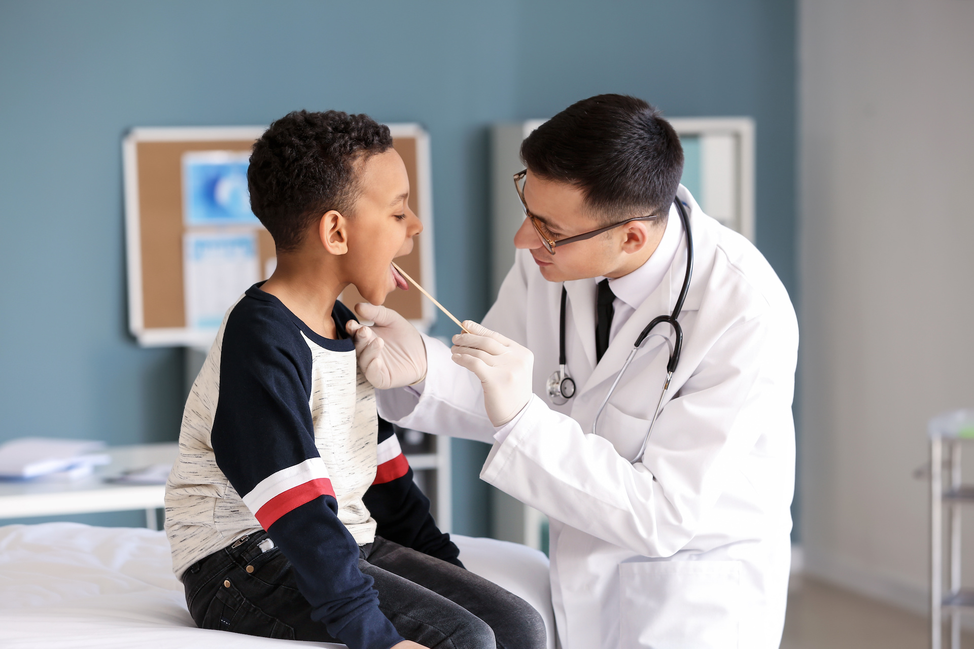 Pediatrician examining African-American boy in clinic